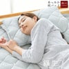 グレーカラーの枕パッドに頬を寄せて眠る女性の写真