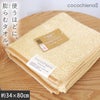 cocochiena2 フェイスタオル カラー:オレンジ を畳んで木製テーブルに置いた商品写真（約34×80cm）