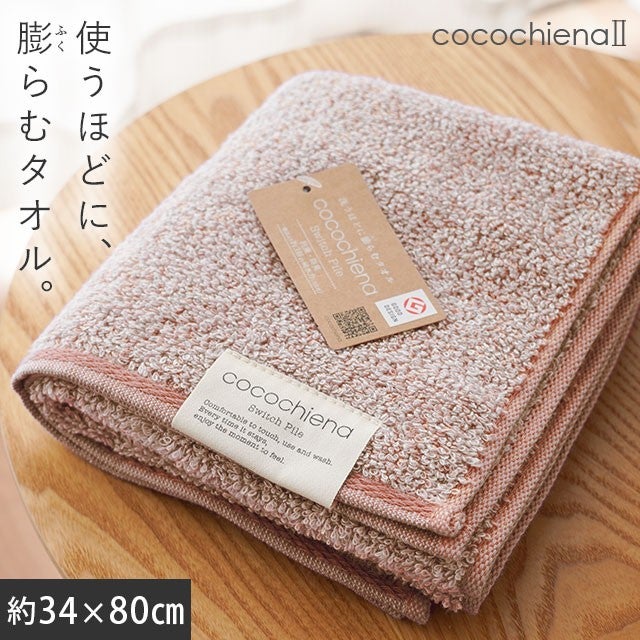 cocochiena2 フェイスタオル カラー:ピンク を畳んで木製テーブルに置いた商品写真（約34×80cm）