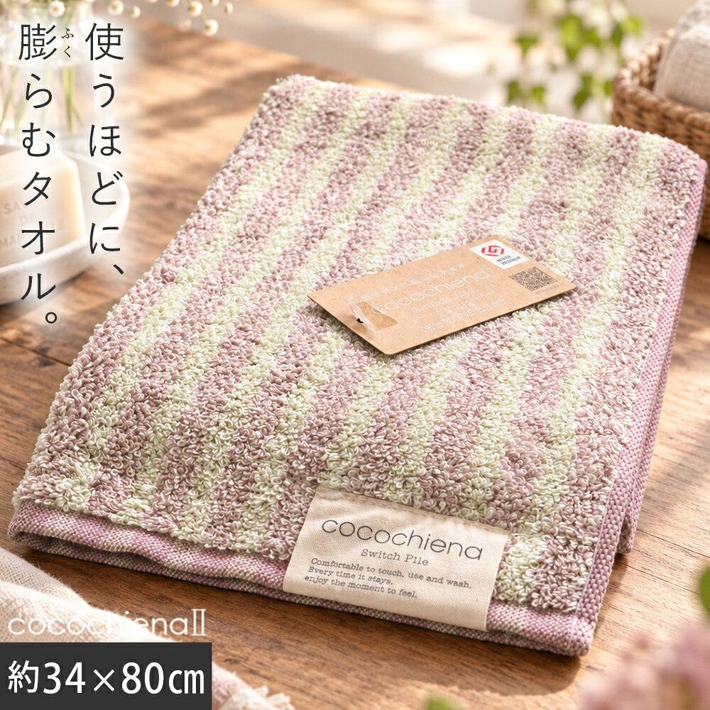 cocochiena2 フェイスタオル カラー:ライン柄/ピンク を畳んで木製テーブルに置いた商品写真（約34×80cm）