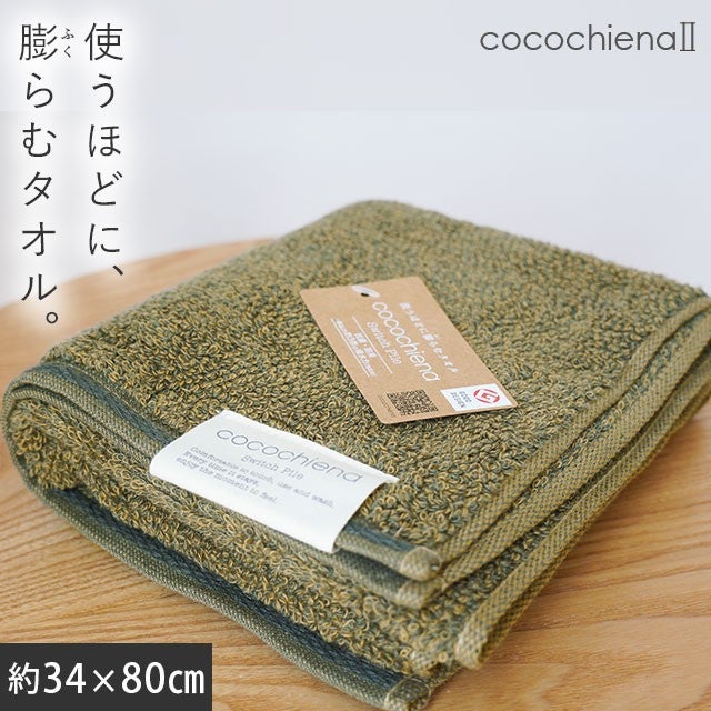 cocochiena2 フェイスタオル カラー:ダークグリーン を畳んで木製テーブルに置いた商品写真（約34×80cm）