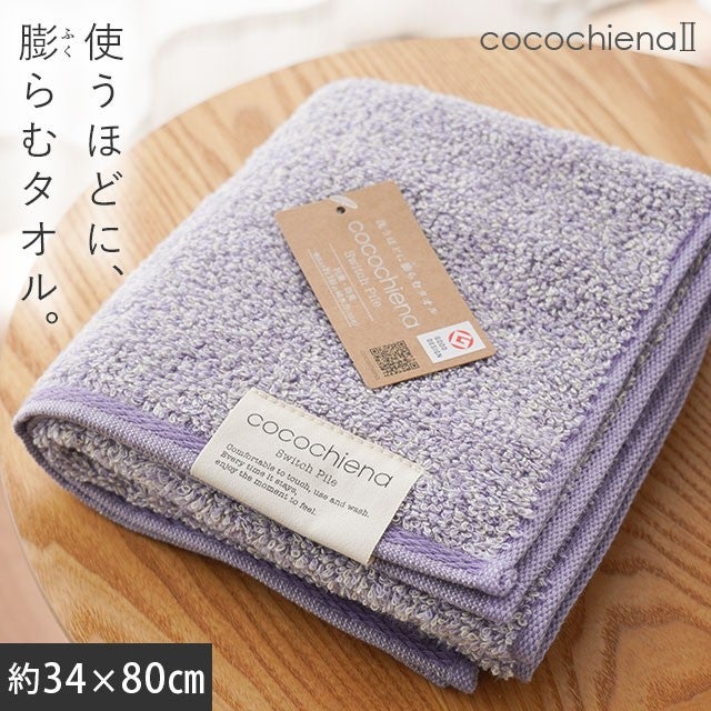 cocochiena2 フェイスタオル カラー:バイオレット を畳んで木製テーブルに置いた商品写真（約34×80cm）