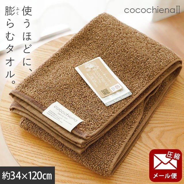 cocochiena2 スリムバスタオル【メール便】 カラー:ブラウン を畳んで木製テーブルに置いた商品写真（約34×120cm）