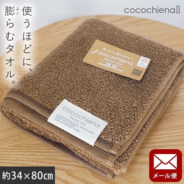 cocochiena2 フェイスタオル【メール便】 カラー:ブラウン を畳んで木製テーブルに置いた商品写真（約34×80cm）