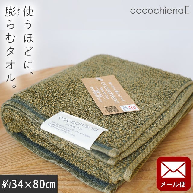 cocochiena2 フェイスタオル【メール便】 カラー:ダークグリーン を畳んで木製テーブルに置いた商品写真（約34×80cm）