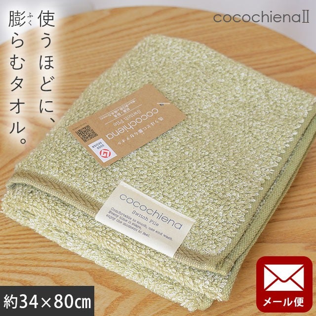 cocochiena2 フェイスタオル【メール便】 カラー:グリーン を畳んで木製テーブルに置いた商品写真（約34×80cm）