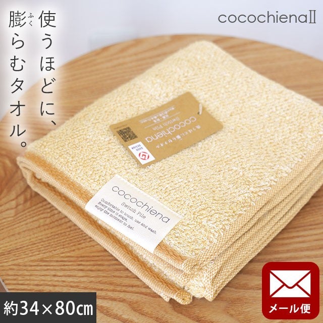 cocochiena2 フェイスタオル【メール便】 カラー:オレンジ を畳んで木製テーブルに置いた商品写真（約34×80cm）