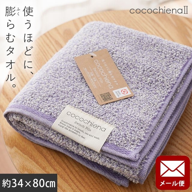 cocochiena2 フェイスタオル【メール便】 カラー:バイオレット を畳んで木製テーブルに置いた商品写真（約34×80cm）